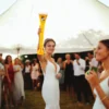 woman hoisting a half yard glass of beer above her head in celebration.