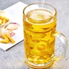 a Masskrug Oktoberfest glass sitting on a table next to a plate of fries.