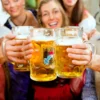 three Bavarian women giving a cheers with their Oktoberfest Masskrug beer glasses.