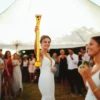 woman raising a full yard glass for a toast at an evening party.